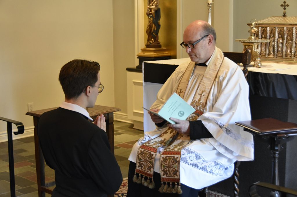 Br Giles kneels before Fr Paul during the ceremony