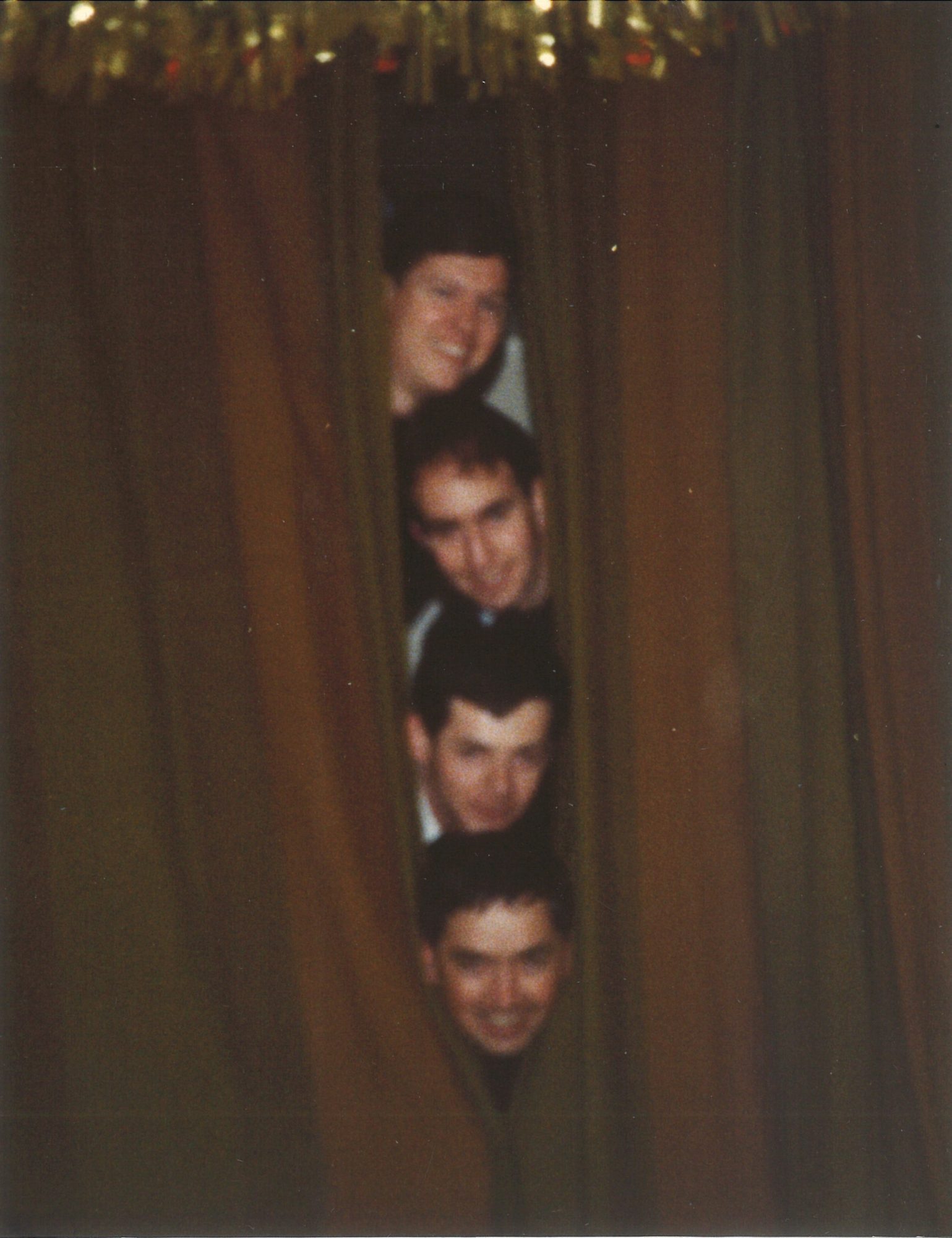 Fr Dan, Fr Juvenal, Br Ted, and Fr David peek out through a curtain at Christmas